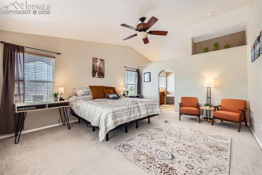 Image 10 of 49: Primary bedroom featuring arched walkways, lofted ceiling, and ceiling fan