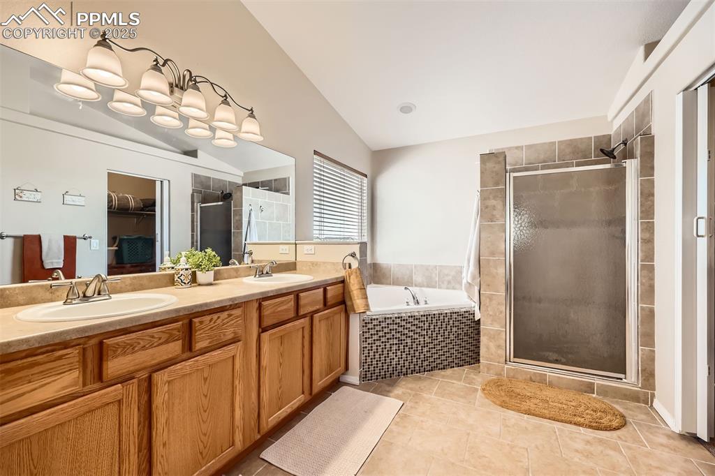 Image 13 of 49: Primary ensuite bathroom with vaulted ceiling, shower, double vanity, and a