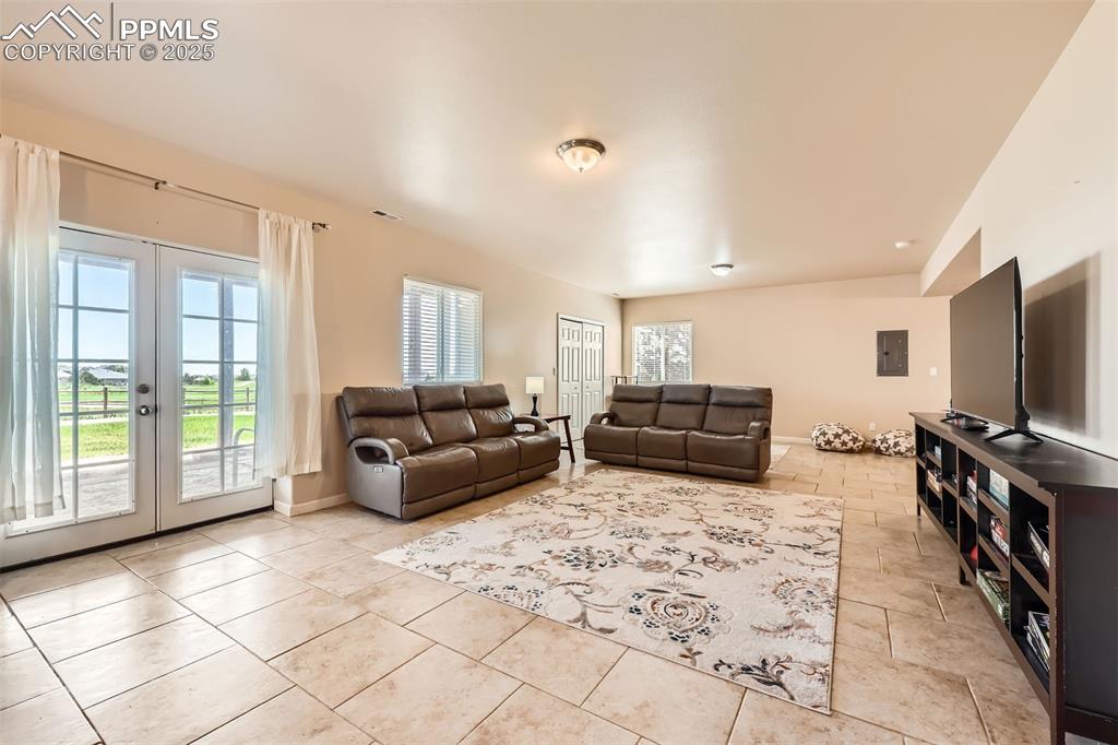Image 22 of 49: Basement living area featuring french doors and tile flooring
