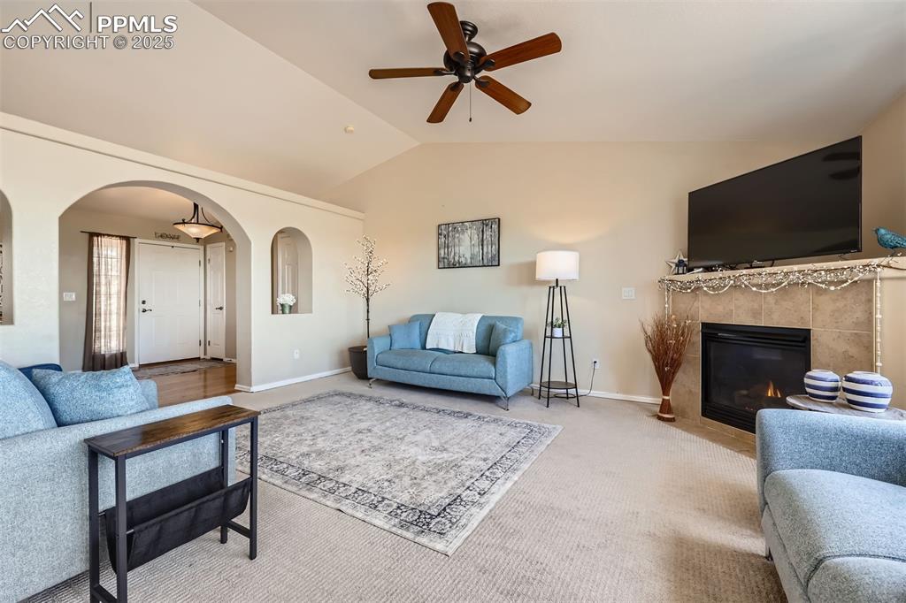 Image 5 of 49: Carpeted living area with arched walkways, ceiling fan, lofted ceiling, and