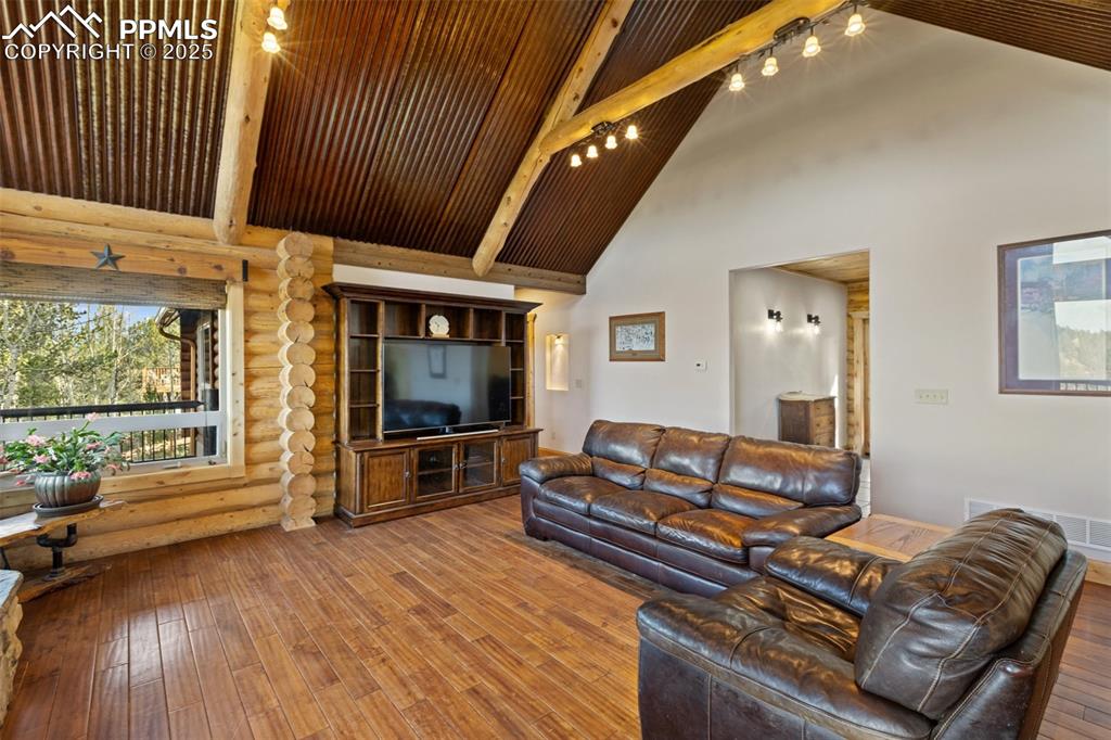 Image 13 of 46: Living area featuring beamed ceiling, hardwood / wood-style floors, high va