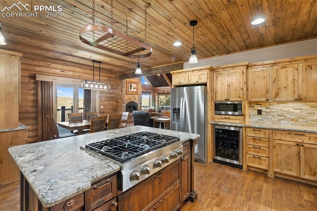 Image 16 of 46: Kitchen featuring light stone counters, stainless steel appliances, pendant