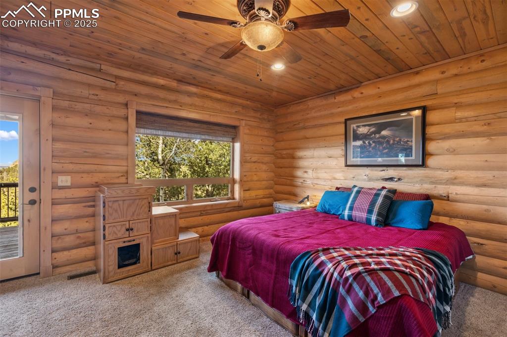 Image 24 of 46: Bedroom with carpet floors, wood ceiling, access to outside, log walls, and