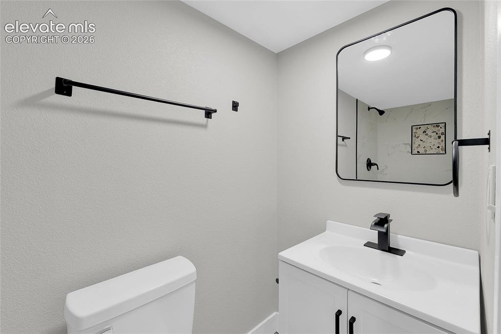 Image 23 of 27: White vanity with integrated sink, matte black faucet, and coordinating har