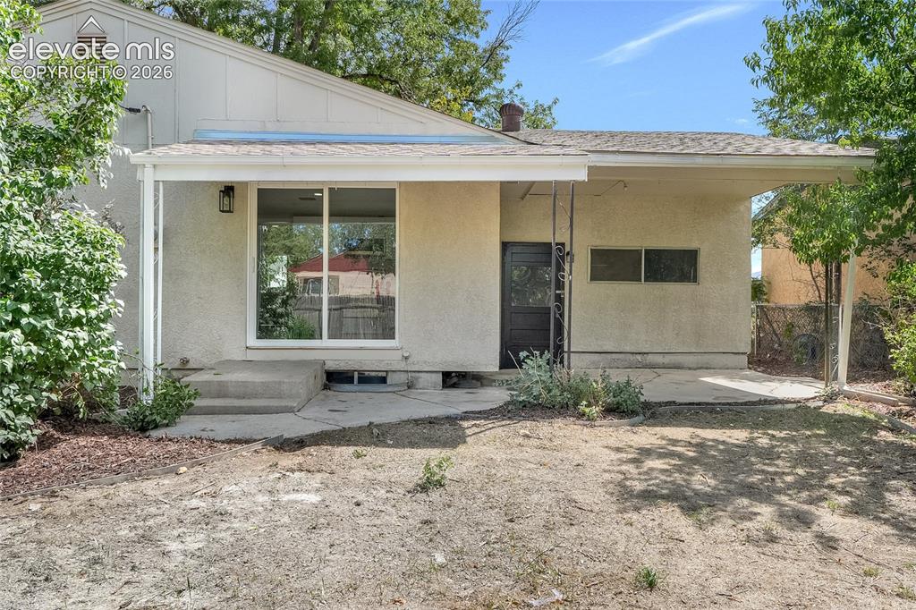 Image 24 of 27: Stucco exterior with a covered patio, featuring a sliding glass door and co