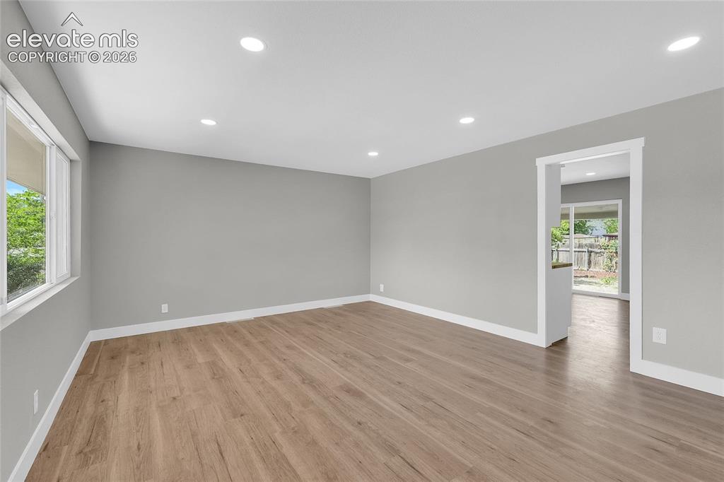 Image 7 of 27: Recessed lighting, wood-finish flooring, and white trim
