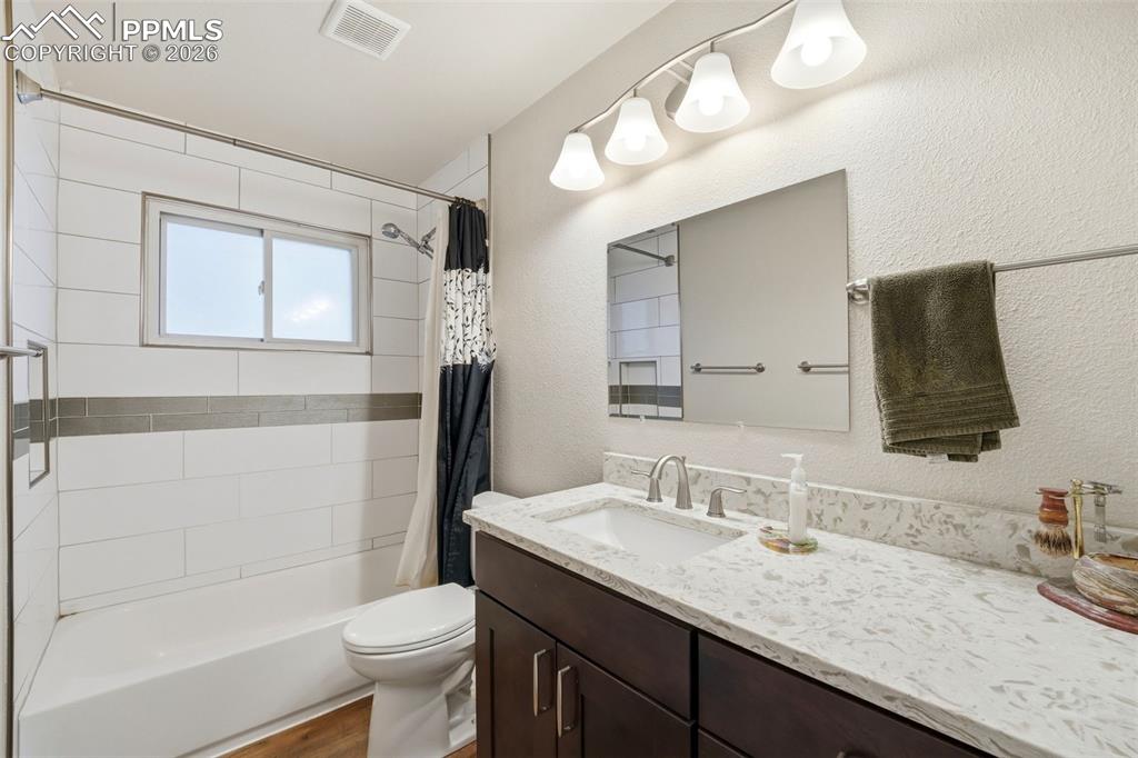 Image 19 of 47: Full bathroom with vanity, shower / bath combo with shower curtain, and a t