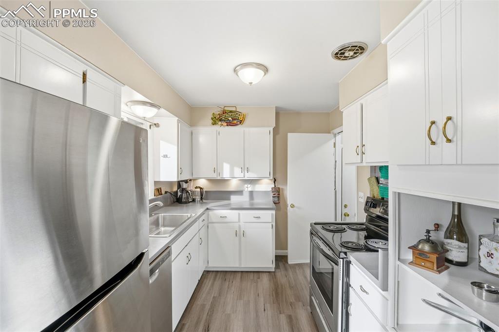 Image 3 of 47: Kitchen with stainless steel appliances, white cabinetry, light countertops