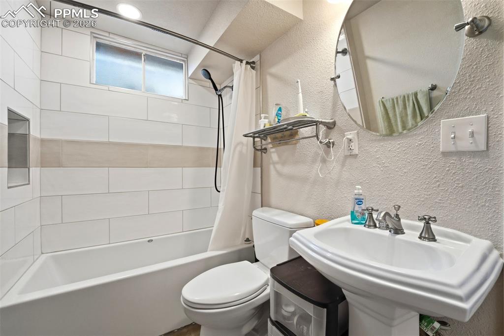 Image 32 of 47: Full bathroom featuring a textured wall and shower / bathtub combination wi