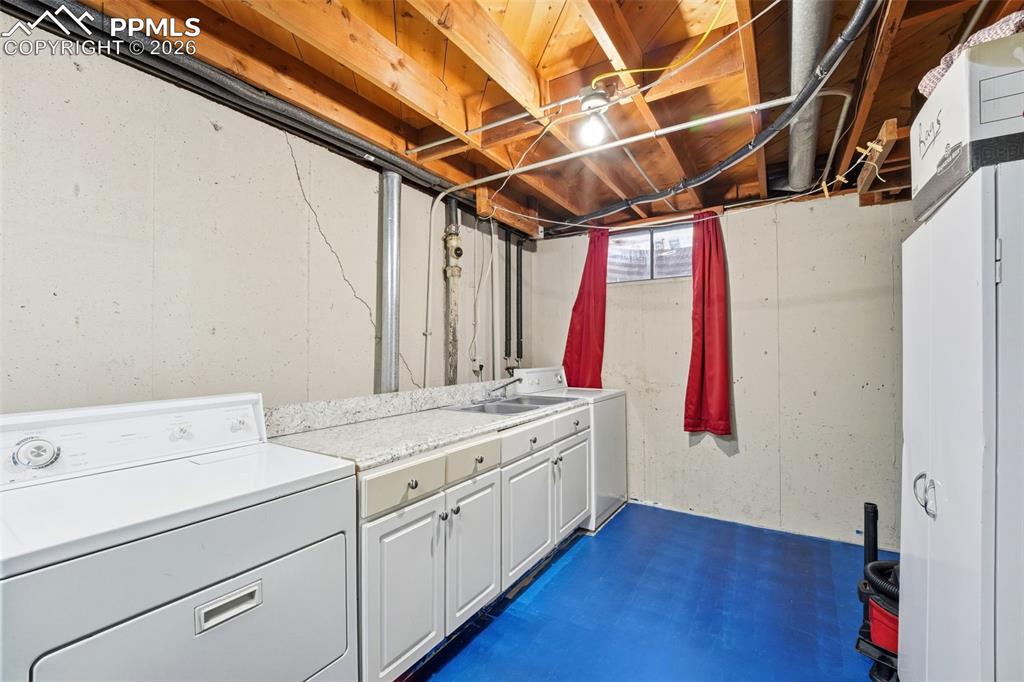 Image 34 of 47: Laundry room featuring cabinet space, concrete flooring, and washing machin
