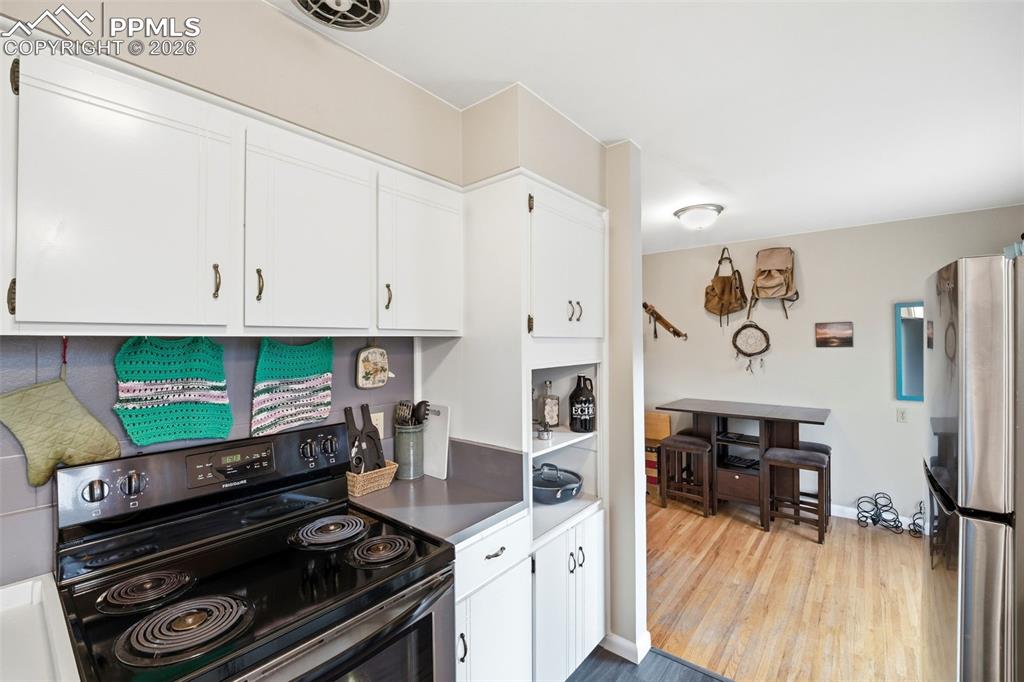 Image 7 of 47: Kitchen featuring black electric range oven, white cabinetry, freestanding 