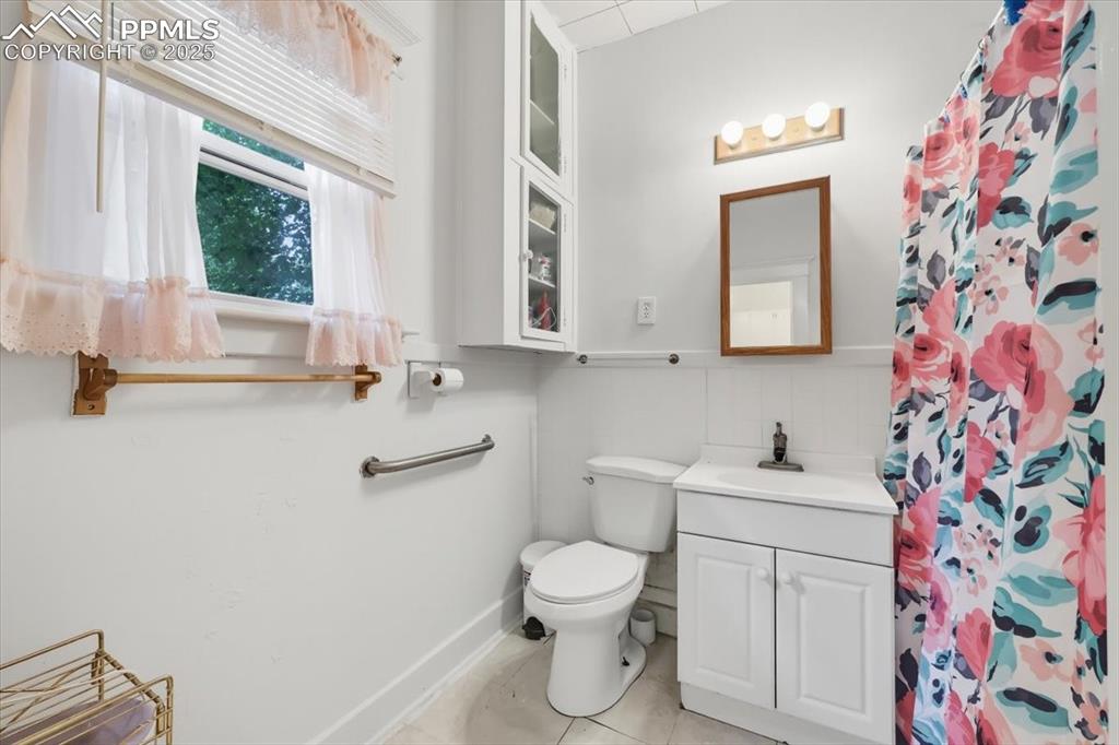Image 12 of 23: Bathroom featuring vanity, light tile patterned floors, and a shower with c