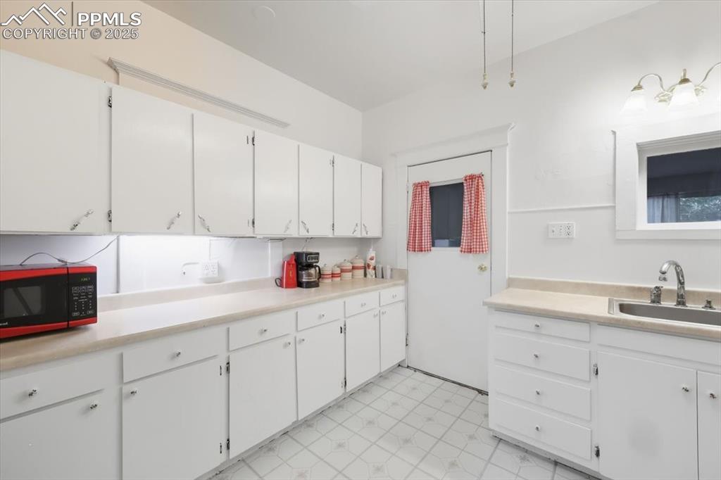 Image 14 of 23: Kitchen with light countertops, white cabinets, and light floors