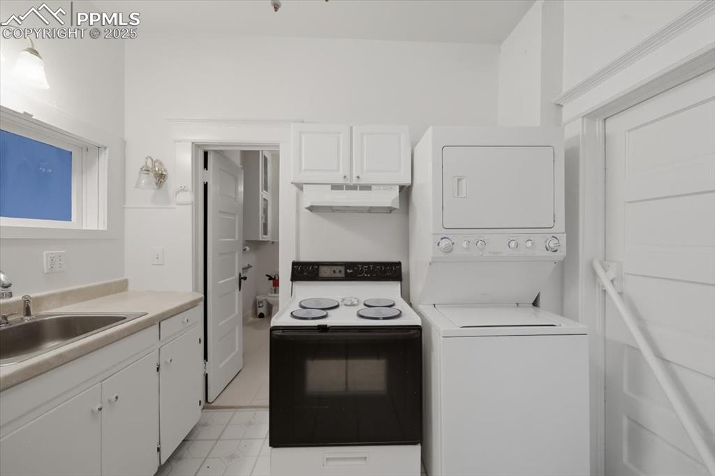 Image 15 of 23: Kitchen featuring electric stove, white cabinetry, light countertops, under