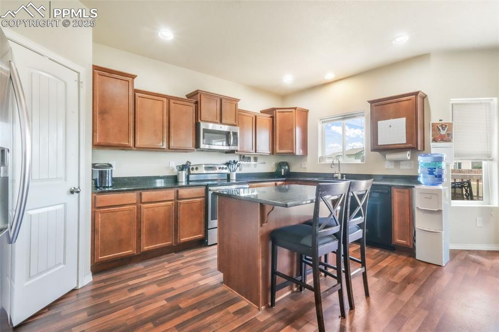 Image 10 of 48: Kitchen with a breakfast bar area, stainless steel appliances, brown cabine