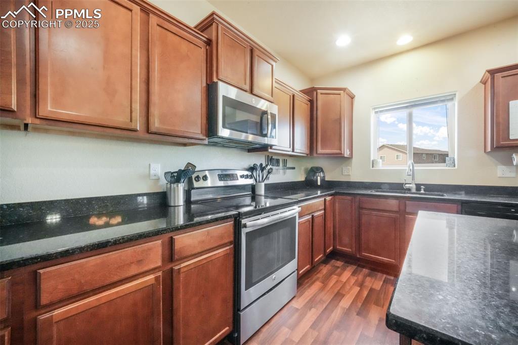 Image 11 of 48: Kitchen featuring appliances with stainless steel finishes, brown cabinets,