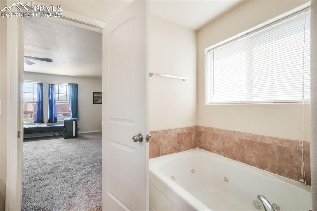 Image 27 of 48: Full bath with a whirlpool tub and ceiling fan