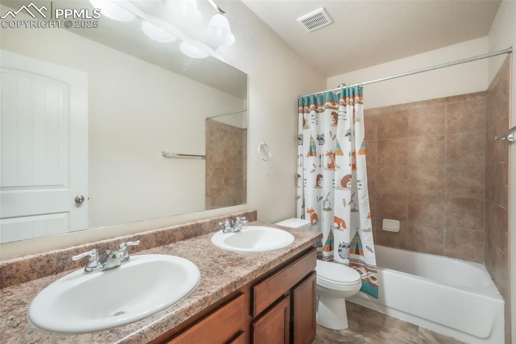 Image 31 of 48: Bathroom with shower / bath combo with shower curtain and toilet