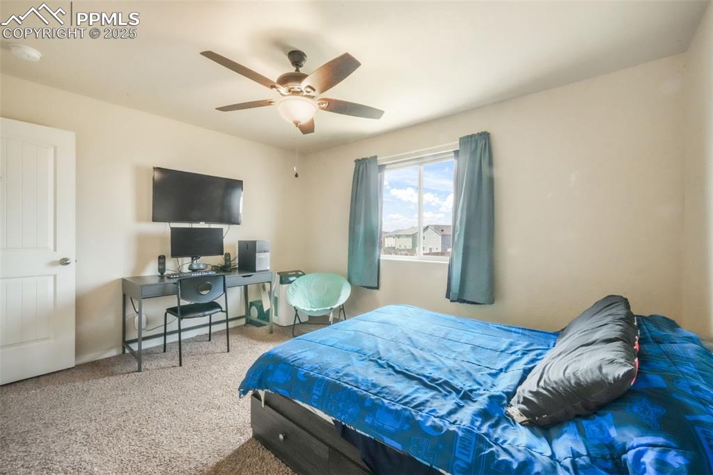 Image 35 of 48: Carpeted bedroom featuring ceiling fan and an office area