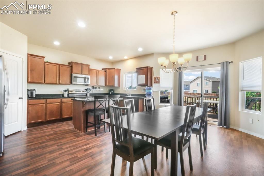 Image 9 of 48: Dining area with dark wood-style flooring, a chandelier, and recessed light