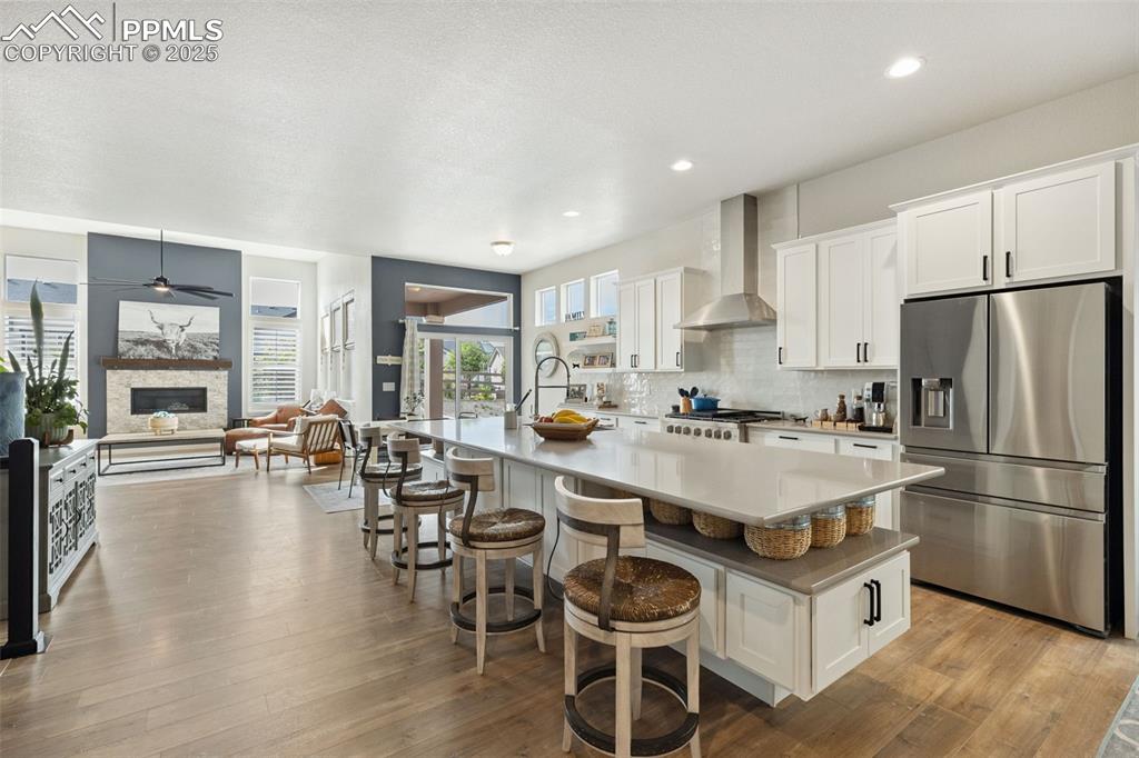 Image 15 of 49: Kitchen featuring stainless steel fridge, wall chimney range hood, a center