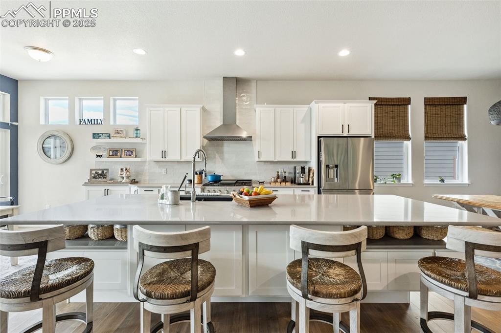 Image 17 of 49: Kitchen featuring stainless steel fridge with ice dispenser, wall chimney e