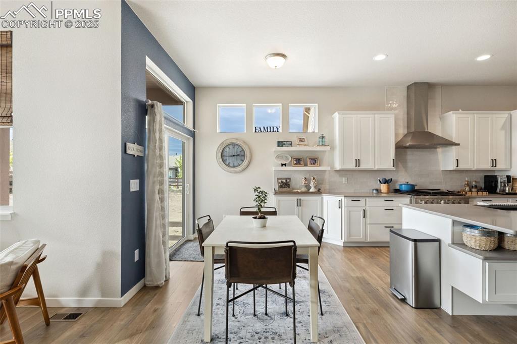 Image 19 of 49: Kitchen featuring wall chimney exhaust hood, decorative backsplash, light w