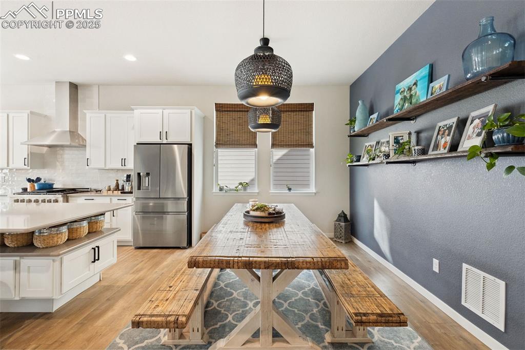 Image 20 of 49: Kitchen with stainless steel refrigerator with ice dispenser, wall chimney