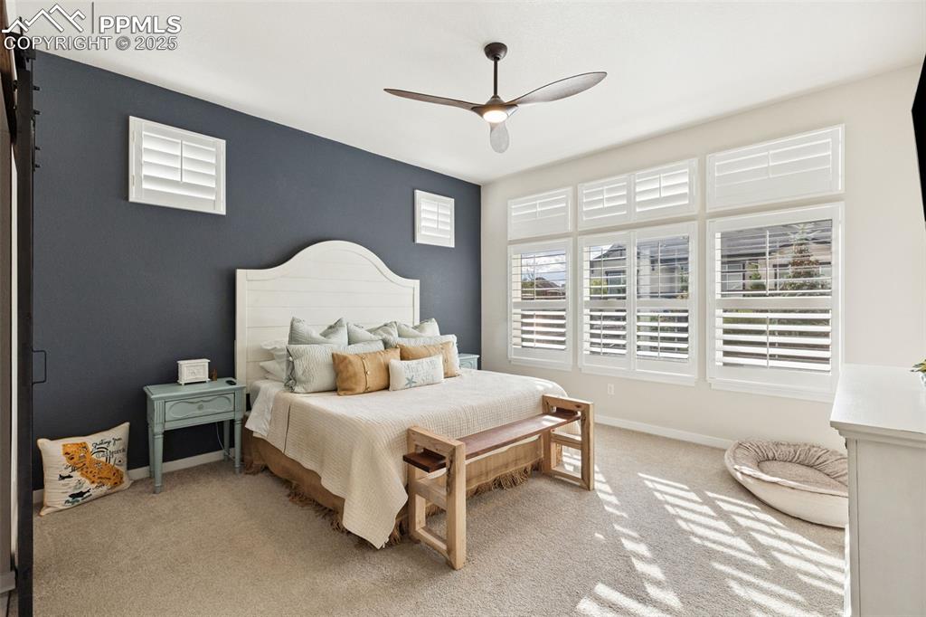 Image 24 of 49: Bedroom with light colored carpet, a barn door, and a ceiling fan