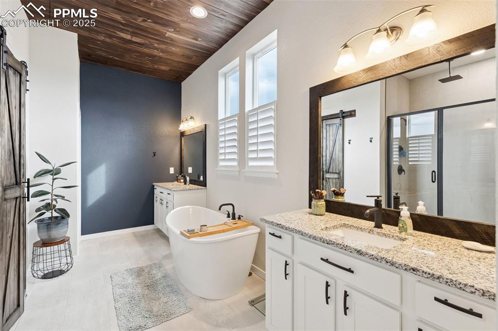 Image 27 of 49: Full bath with wooden ceiling, a shower stall, two vanities, a freestanding