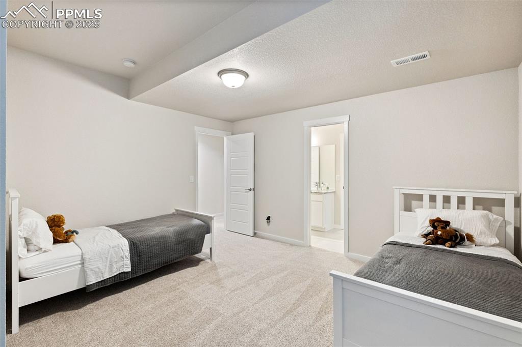 Image 30 of 49: Carpeted bedroom with ensuite bathroom and baseboards