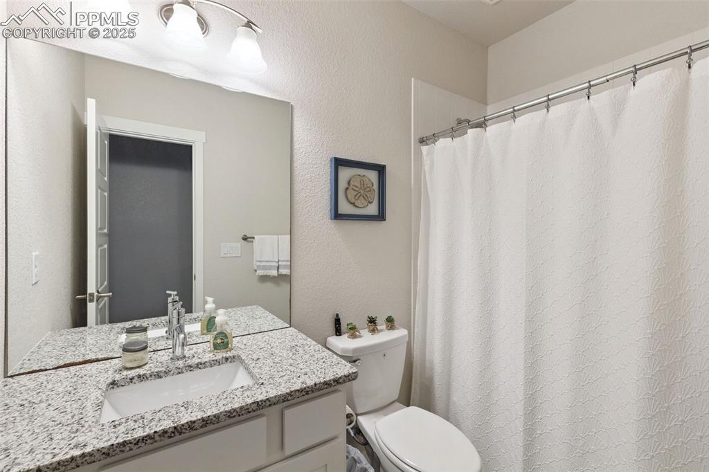 Image 34 of 49: Full bathroom featuring vanity, a textured wall, and a shower with shower c