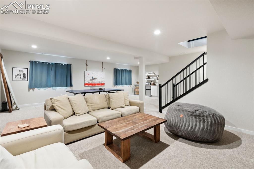 Image 38 of 49: Living area with light carpet, recessed lighting, and stairs