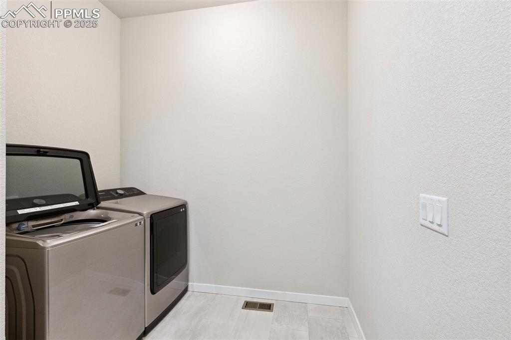 Image 42 of 49: Laundry area featuring washing machine and clothes dryer and baseboards