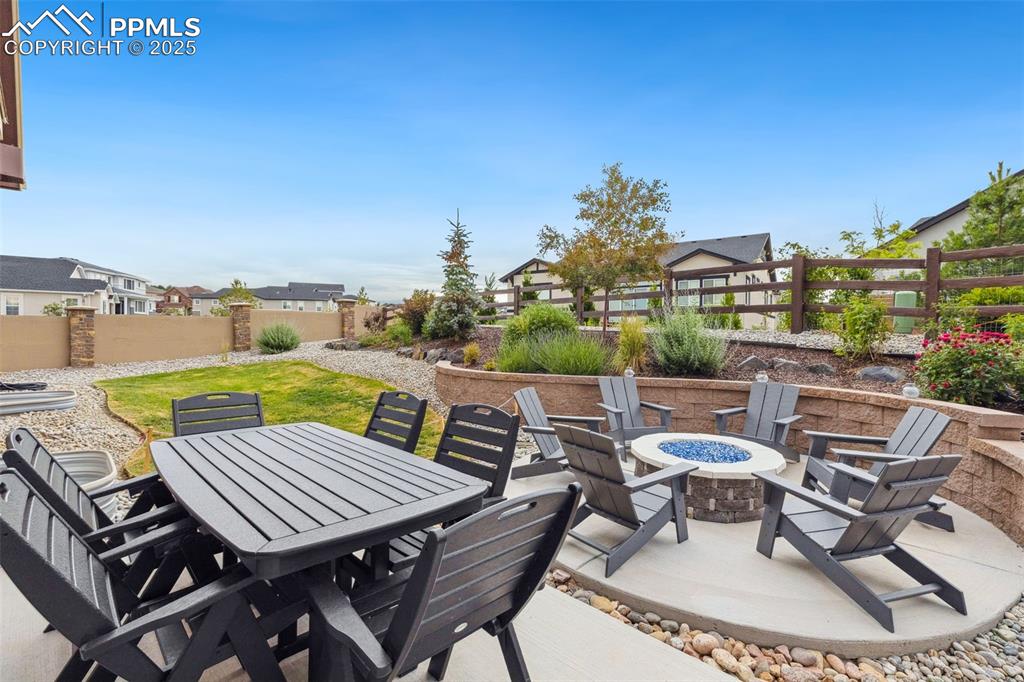 Image 43 of 49: Fenced backyard featuring a fire pit and a patio area