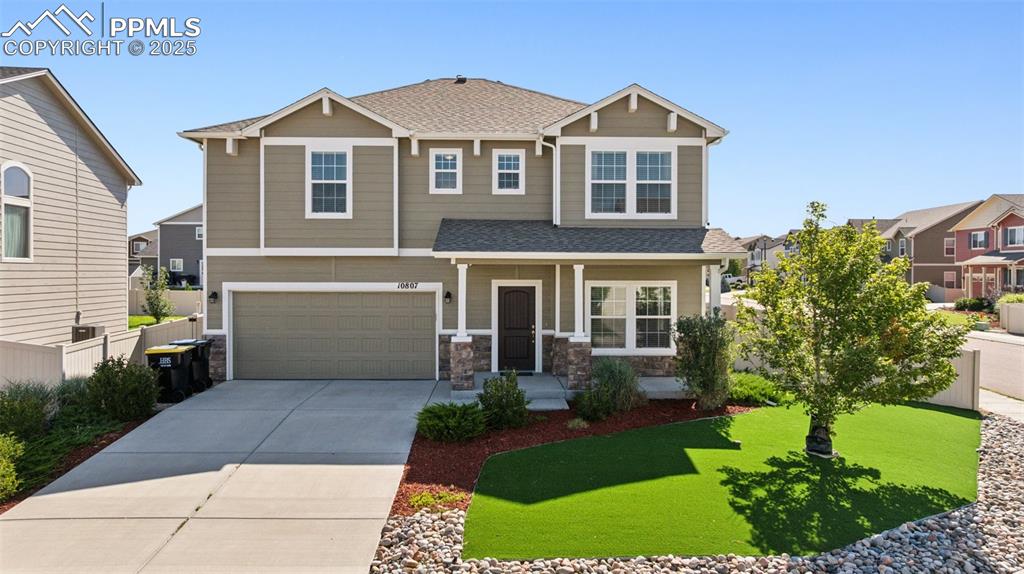 Caption: Craftsman house with roof with shingles, a porch, concrete driveway, a garage, and stone siding