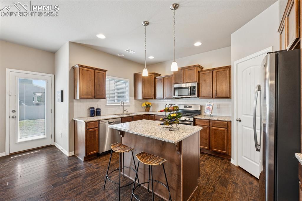 Image 10 of 39: Kitchen featuring stainless steel appliances, brown cabinets, backsplash, p