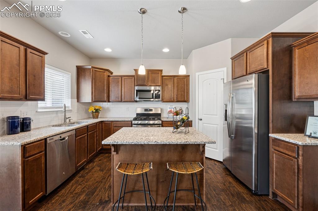 Image 11 of 39: Kitchen featuring appliances with stainless steel finishes, decorative ligh
