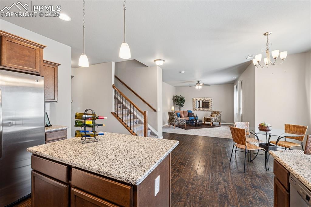 Image 12 of 39: Kitchen with hanging light fixtures, dark wood finished floors, appliances 