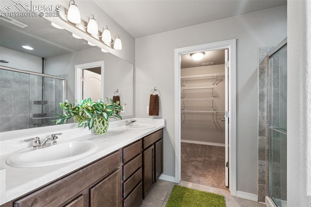 Image 17 of 39: Bathroom with light tile patterned floors, double vanity, a stall shower, a