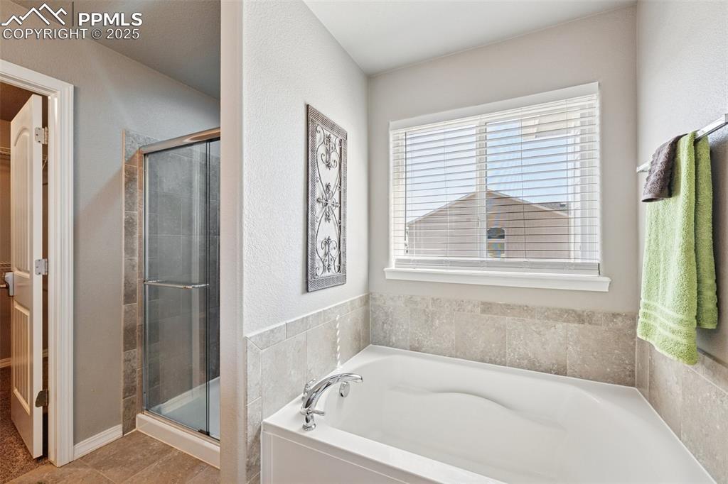 Image 18 of 39: Full bath featuring a stall shower, a bath, and tile patterned flooring