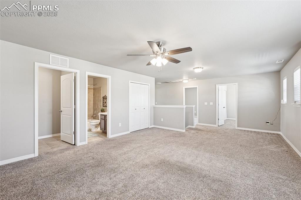 Image 24 of 39: Unfurnished bedroom with ensuite bath, light colored carpet, a closet, and 