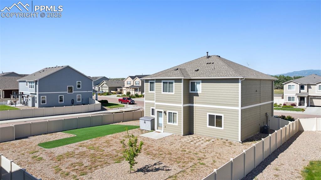Image 32 of 39: Back of house with a residential view, a fenced backyard, and roof with shi