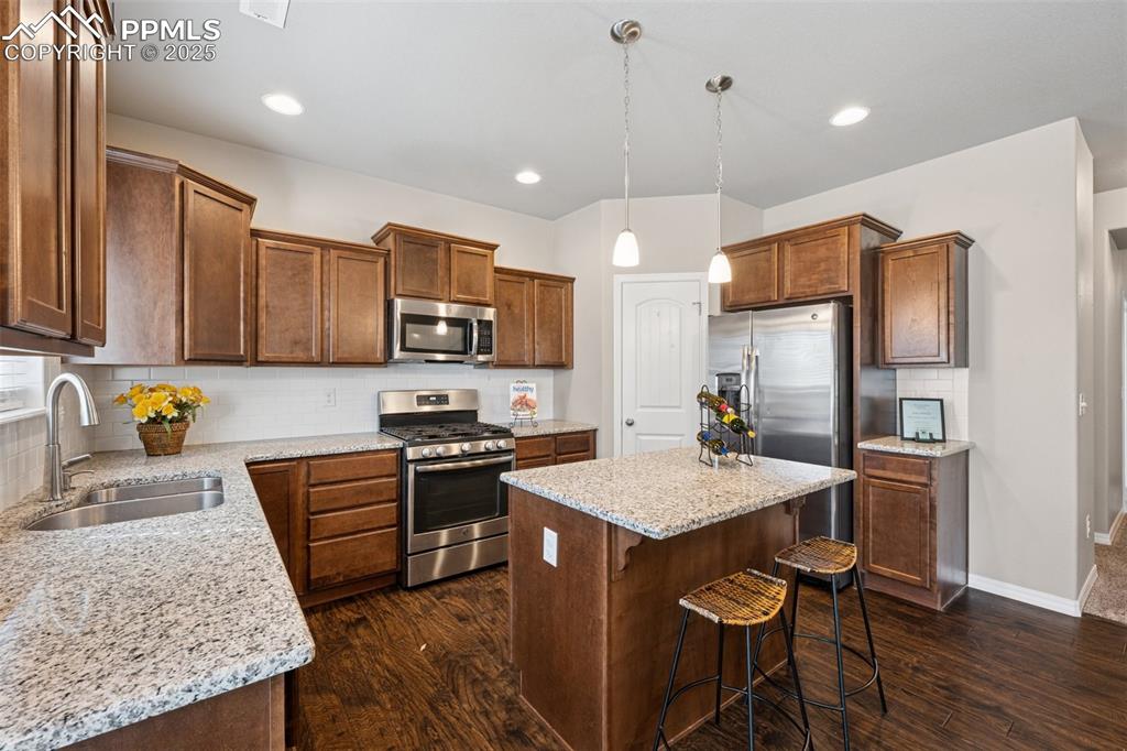 Image 8 of 39: Kitchen featuring decorative backsplash, decorative light fixtures, stainle