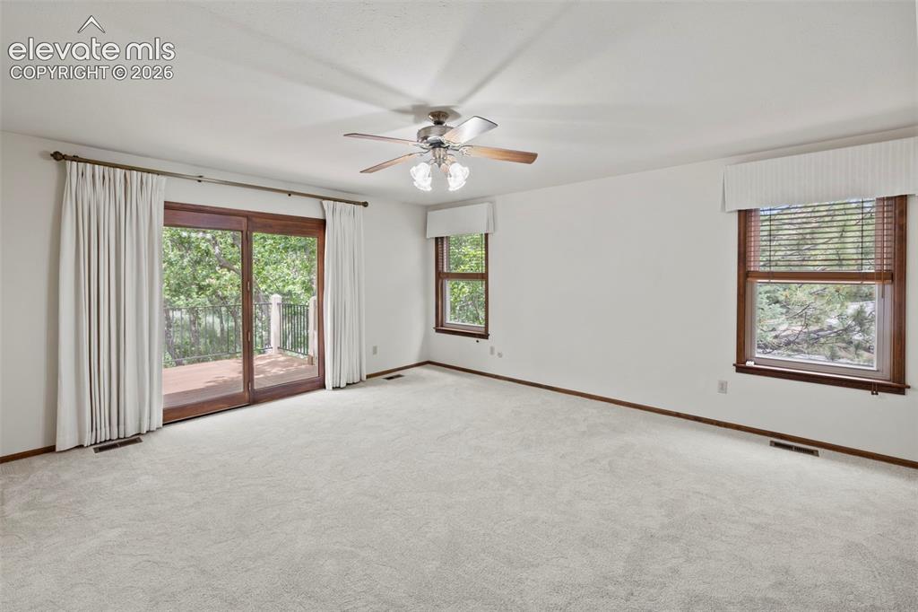 Image 12 of 30: Large Primary Bedroom with new carpet and a door that leads to the back dec
