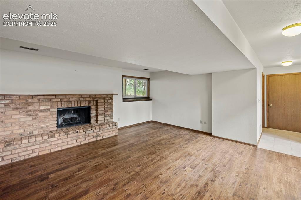 Image 17 of 30: Lower level family room with a fireplace and a wetbar