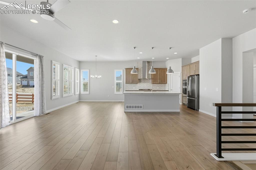 Image 12 of 48: Expansive great room with luxury vinyl plank flooring, open staircase, and 