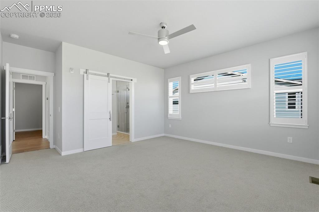 Image 22 of 48: Generously sized bedroom with plush carpet, ceiling fan, and large windows 
