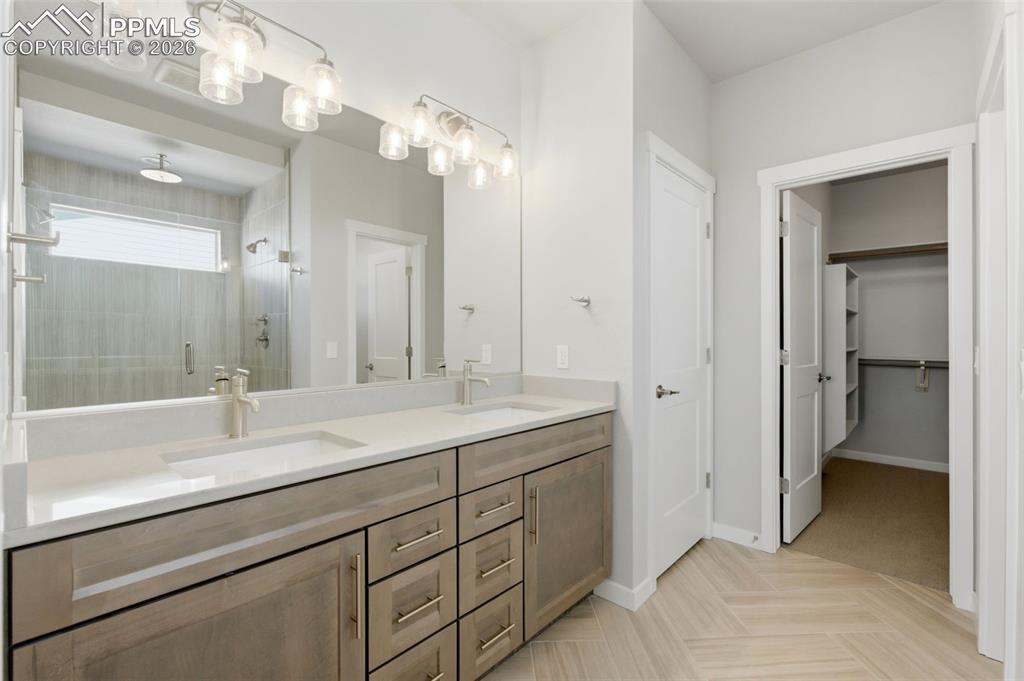 Image 23 of 48: Primary bath with dual-sink vanity, recessed lighting, and walk-in closet a