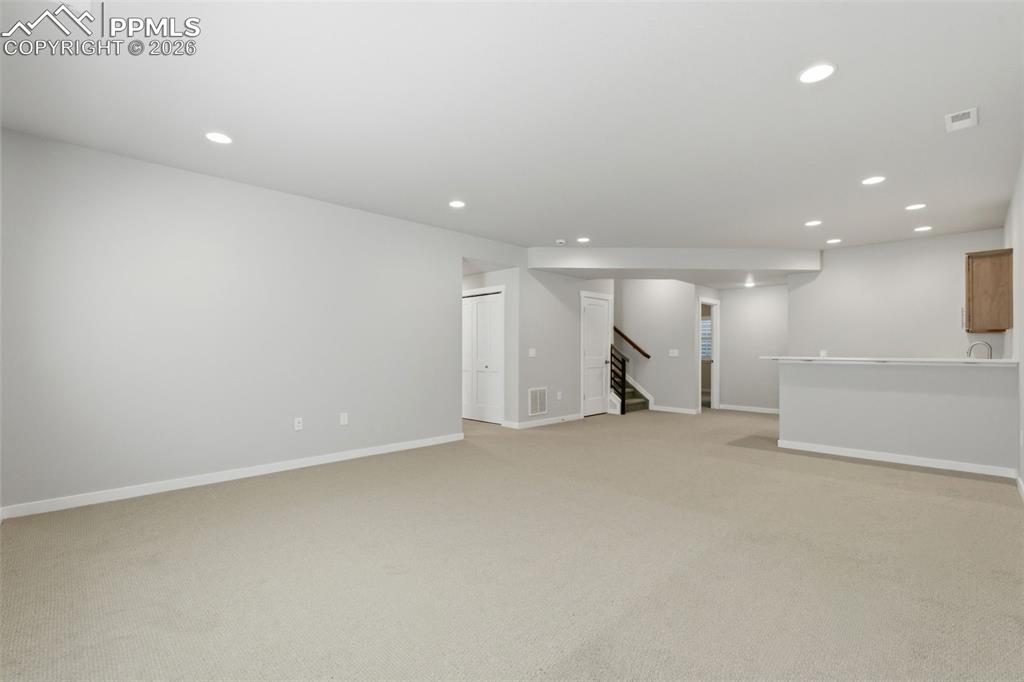 Image 29 of 48: Spacious finished basement with neutral carpet and egress window - ideal fo